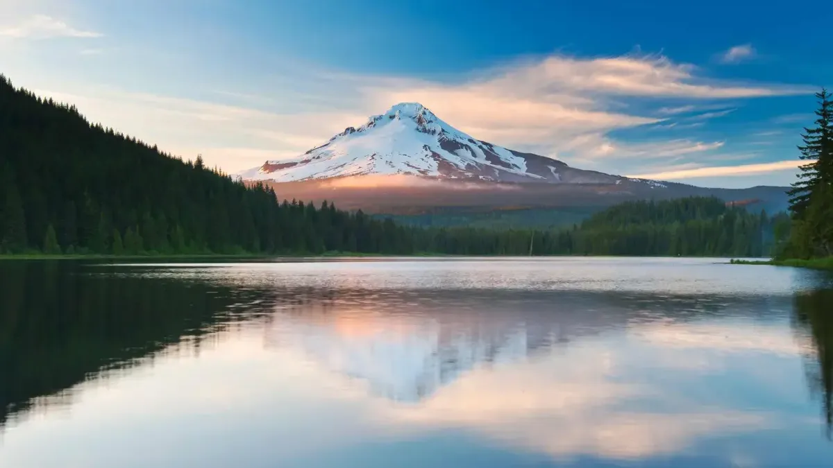 Scenic photo of a snow-capped mountain reflected in a calm lake