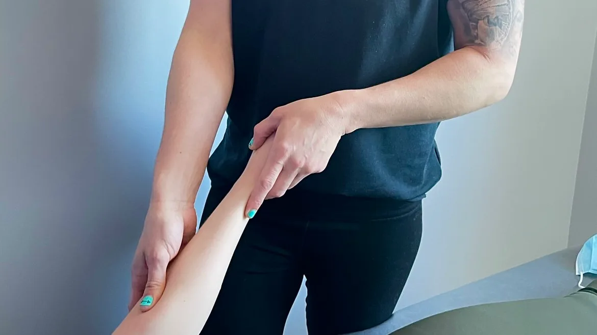 Therapist examining a patient's forearm during a hands-on assessment