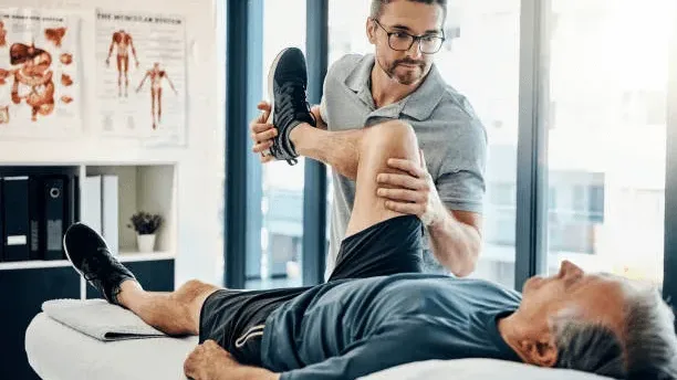 Physical therapist assessing a patient's knee and hip during a physical therapy session