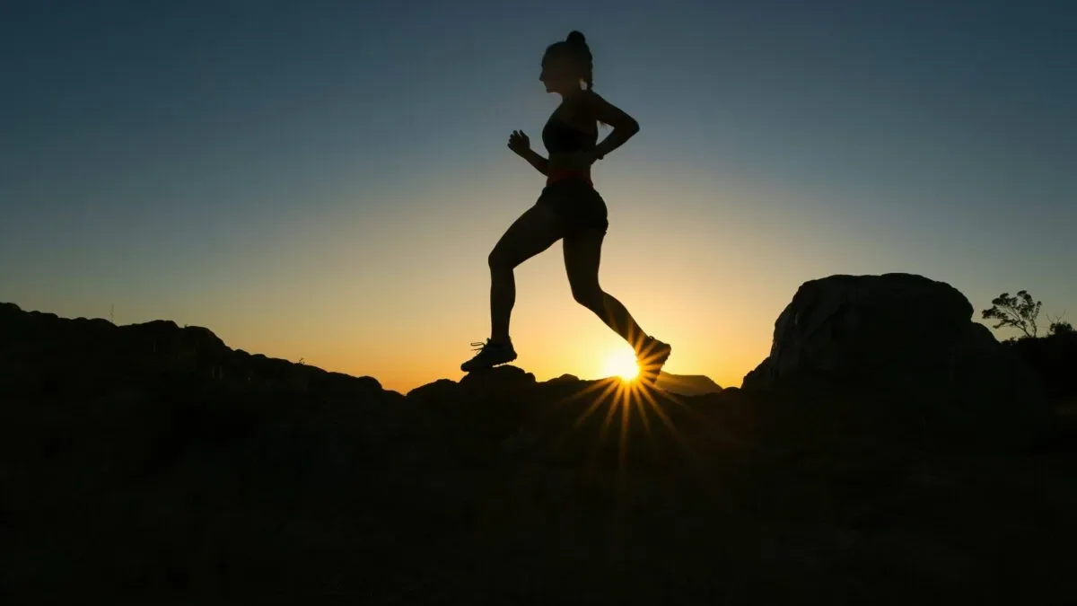 A runner pausing to hold their knee in discomfort during a run