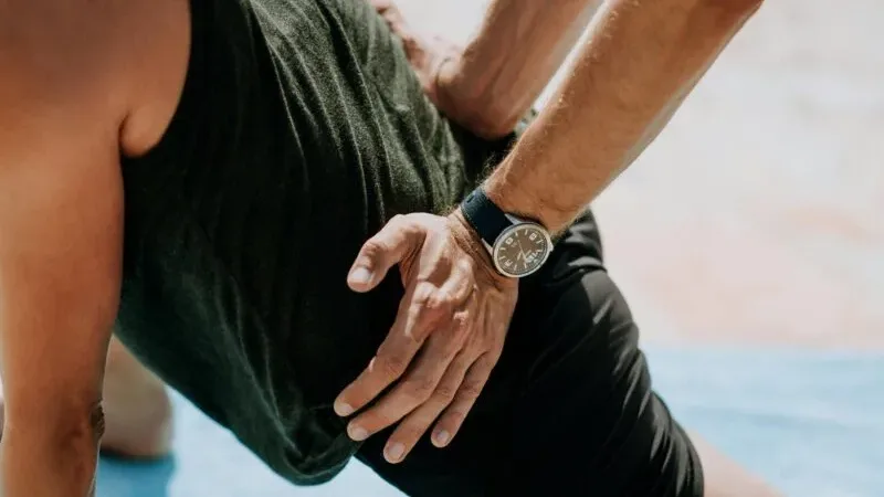 A person holding their lower back and hip area due to psoas muscle tightness