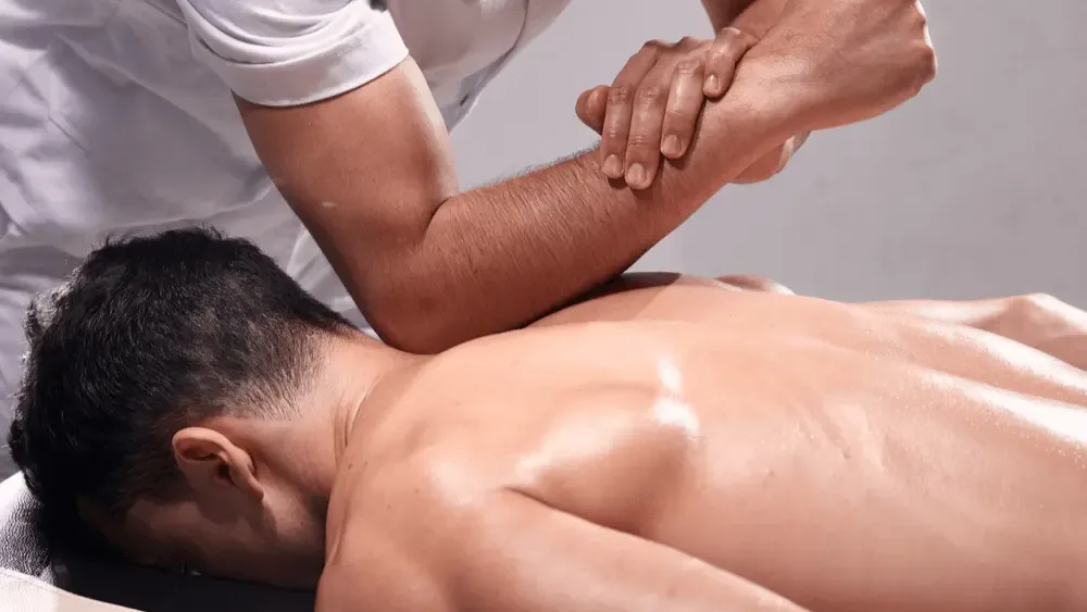 Therapist performing hands-on manual therapy on a patient's upper back and shoulder