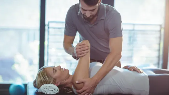 A physical therapist performing shoulder joint mobilization on a patient