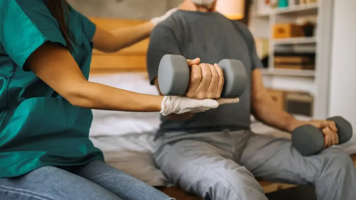 Physical therapist assessing a patient's elbow and wrist mobility and grip strength