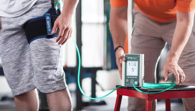 Patient using blood flow restriction cuffs during a light-load strength session